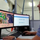 Homem olha para tela de computador com mapas