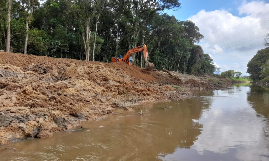 Máquina escavadeira em margem de rio