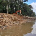 Máquina escavadeira em margem de rio
