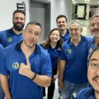 Homens e mulheres com uniforme azul posam para foto
