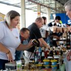 Mulher mostra mel para homem em stand em feira