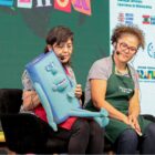 Duas mulheres sentadas em cadeiras em palco contam histórias