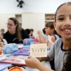 Menina de uniforme em sala de aula sorri para a câmera