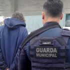 Agente da Guarda Municipal com farda azul segura e conduz homem