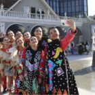 Bailarinas com figurino tiram selfie em praça com escultura de bailarina
