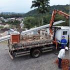 Homens com capacetes e uniformes instalam equipamentos de energia elétrica, em cemitério