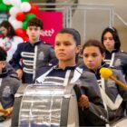 Alunos e alunas com uniformes e instrumentos em uma fanfarra
