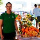 Mulher ao lado de stand com laranjas em feira