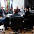 Homens e mulheres sentados em volta de uma mesa em gabinete
