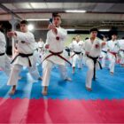 Meninos com quimono treinam karatê em tatame em novo centro de lutas