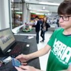 Menino de óculos manuseia kit de robótica em escola