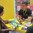 Homem apresenta folhetos e conversa com duas mulheres