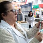 Mulher profissional da saúde manipula frasco e vacina em terminal de ônibus
