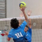 Dois meninos disputam bola em rede de vôlei
