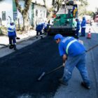 Homens trabalham em rua colocando capa asfáltica