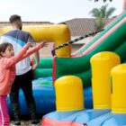 Crianças brincam em brinquedo inflável observadas por adultos