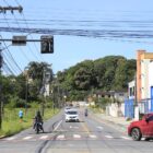 Rua com carros e motocicletas, além de pedestre