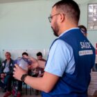 Homem em pé fala com pessoas sentadas em treinamento