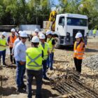 Pessoas com capacete e colete visitam canteiro de obras