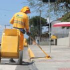 Homem de uniforme amarelo usa varrourão para pintar calçada com tinta amarela