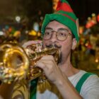 Homem fantasiado de duende toca trompete
