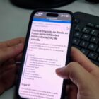 Mulher segura celular e na tela está escrito "Destinar Imposto de Renda ao Fundo para a Infância e Adolescência (FIA) de Joinville"
