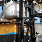 Dois homens trabalham em máquina com equipamentos de segurança