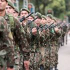 Homens do exército com armas e uniformes desfilam em evento da independência