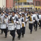 Alunos de fanfarra, com instrumentos e roupa especial, desfilam em avenida