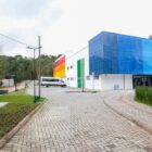 Construção nova do NAIPE em branco com detalhes coloridos, rua e paisagismo