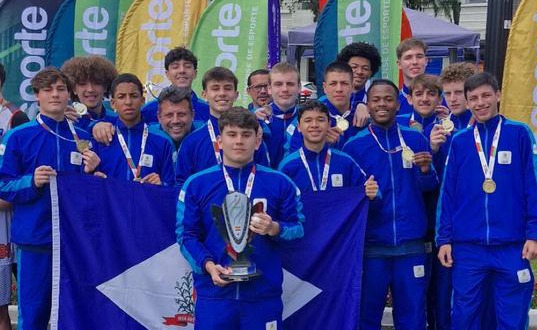 Atletas seguram a bandeira de Joinville enquanto comemoram título na Olesc