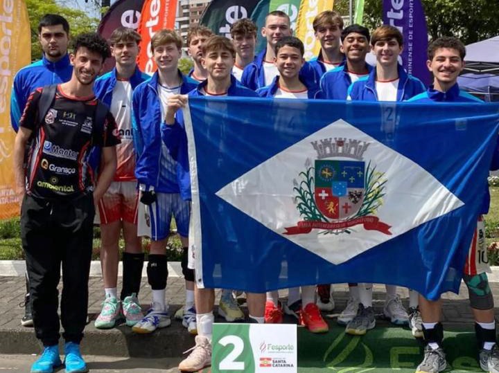 Atletas seguram a bandeira de Joinville enquanto comemoram título na Olesc