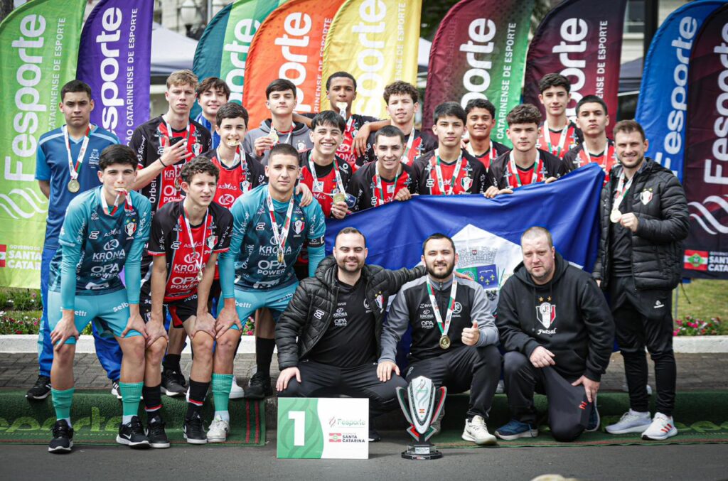 Atletas seguram a bandeira de Joinville enquanto comemoram título na Olesc