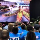 Pessoas sentadas em cadeiras assistem telão com apresentação do projeto paisagístico da Festa das Flores