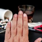 pessoa estende a mão em sinal de rejeição às drogas que estão na frente dele