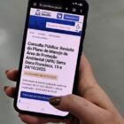 Mão segura celular que está na página da consulta pública sobre Plano de Manejo da APA Serra Dona Francisca