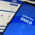 Pessoa segura celular e na tela está escrito "cadastro único"