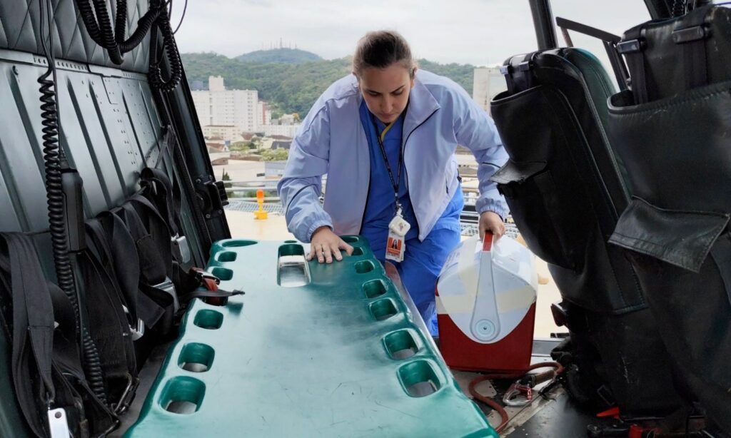 Mulher segurando caixa de transporte vermelha com coração entra em helicóptero