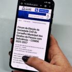 Pessoa segura celular e na tela tem informações sobre eleição de conselheiros