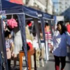 Pessoas caminham em feira de rua com barracas de artesanato