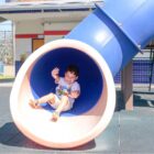 Menino sorrindo desce escorregador tubular colorido em CEI