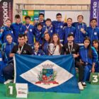 Adolescentes vestidos com uniforme azul seguram bandeira de Joinville