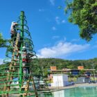 Dois homens trabalham na estrutura de uma árvore de Natal na praça Dario Salles
