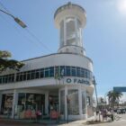 Prédio branco com janelas e torre de vidro na esquina entre ruas
