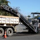 Caminhão e máquina em rua em processo de pavimentação