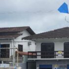 Menino com uniforme escolar segura linha de pipa azul que voa no céu