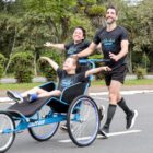 Casal conduz criança em triciclo adaptado para corrida