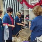 Quatro mulheres idosas vestidas com jaleco azul manuseiam roupas