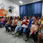 Famílias sentadas em cadeiras em auditório a espera de sorteio