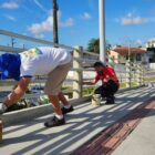 Dois homens pintam estrutura de ponte